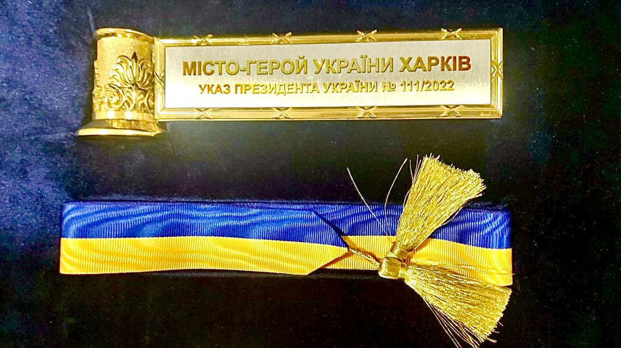 Стрічка міста-героя на прапор Харкова (Фото: Telegram Ігоря Терехова) Харків – місто-герой України. Зеленський передав почесний знак меру міста – відео, фото